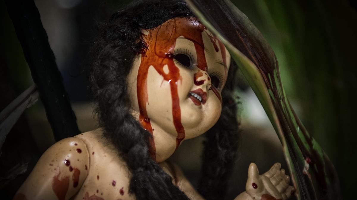 Czarnowłosa lalka z czarnymi oczami pokryta krwią.