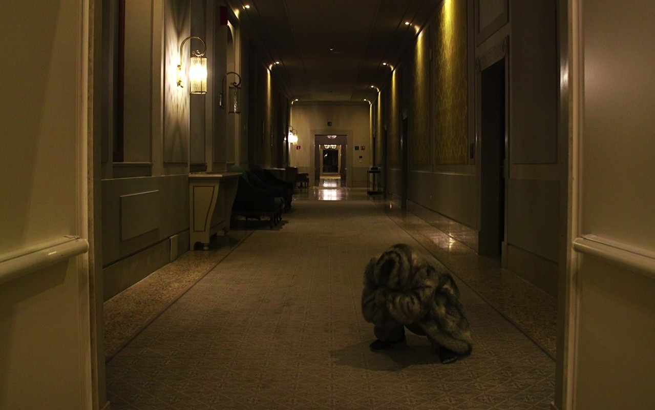 przykucnięta postać w futrze na korytarzu