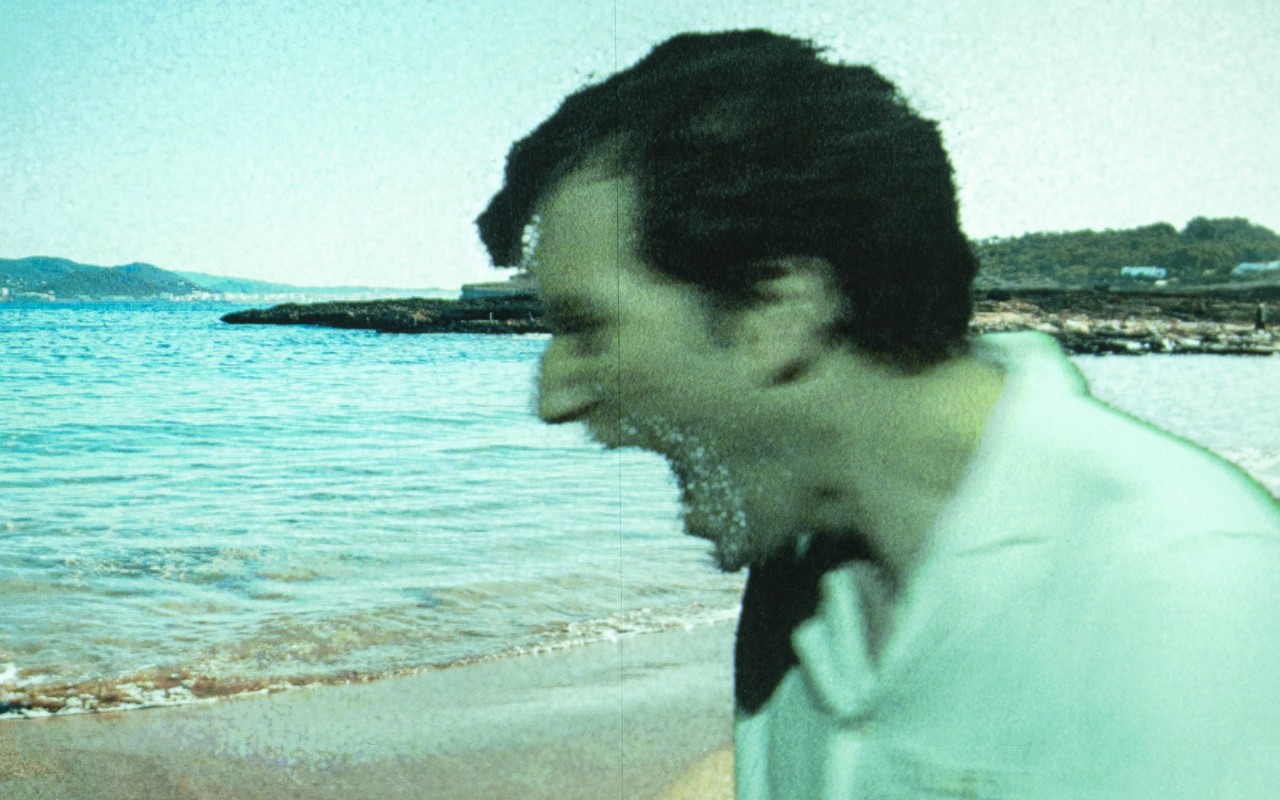 Postać mężczyzny widziana w planie od ramion w górę, w profilu z ustami ułożonymi do krzyku, komputerowo nałożona na obraz plaży